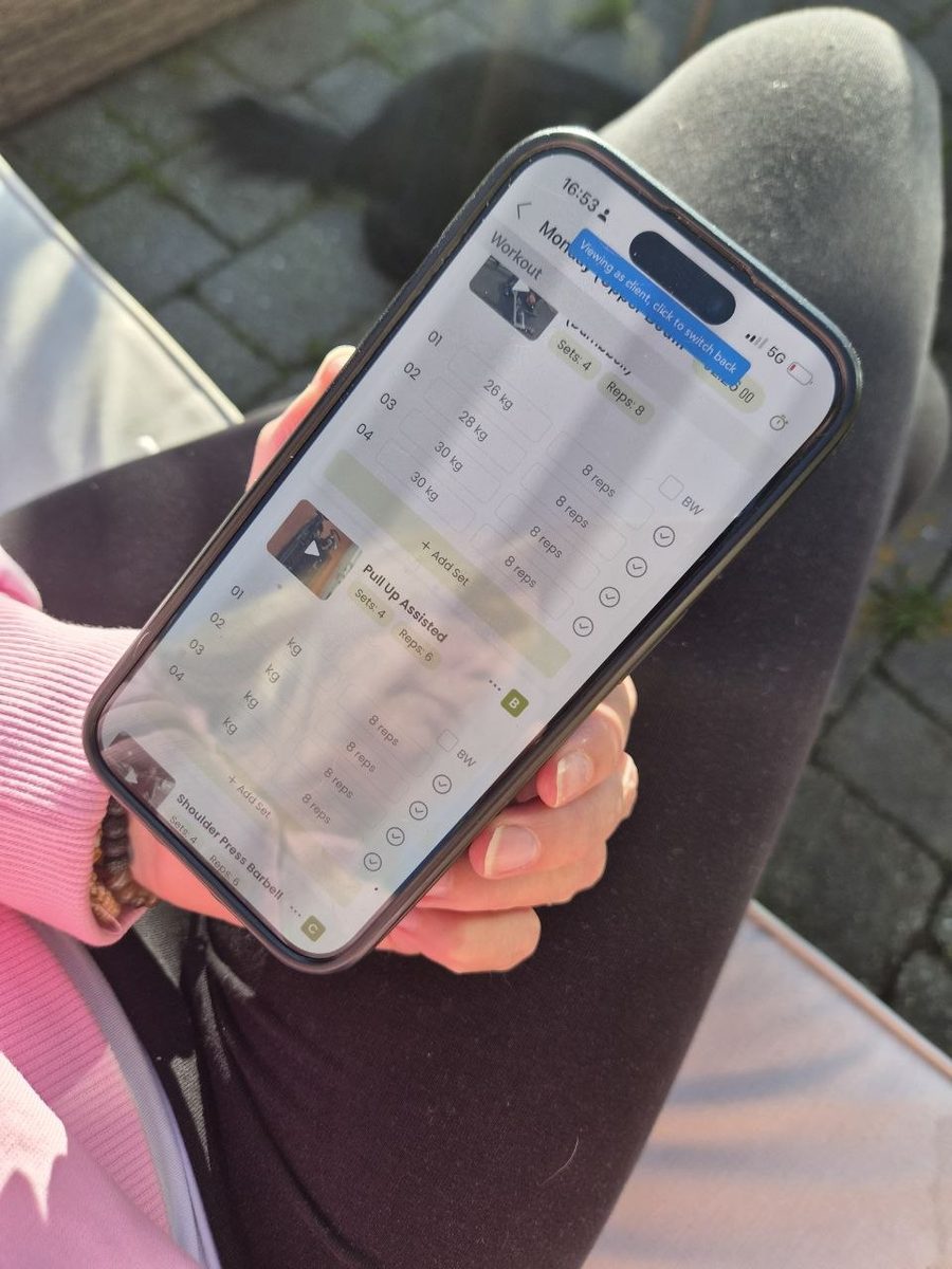 A client logging her sets and weights in the Coach Morgan app on her phone